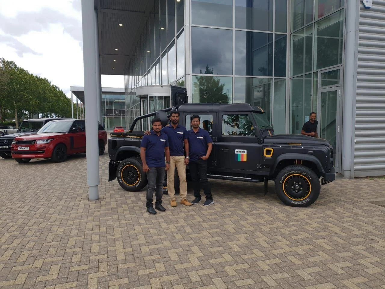 Group beside a vehicle outside a London building, from the August 2018 Miwhip archive